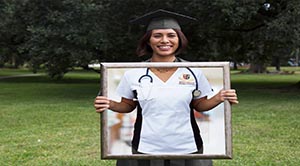 A graduating student holds up a frame showing herself as a practicing nurse