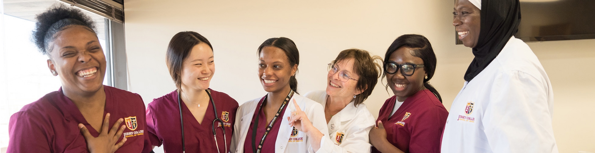 Group of nursing students and instructors smiling and laughing together in a classroom.